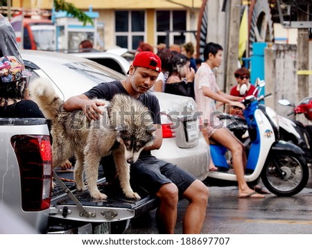 Chachoengsao Province 13 April 2014: Thai man and his siberian husky dog celebrate Songkran festival splashing water with bowls and water spray guns on the street in cities of Thailand