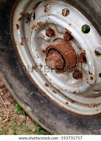 old aged weathered abandoned black rusty metal iron wheel leaving outdoor with old cracked rubber tyre close up.