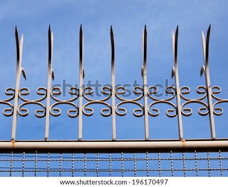 home metal fence with mesh iron wires and old vintage style long sharp spikes on the top