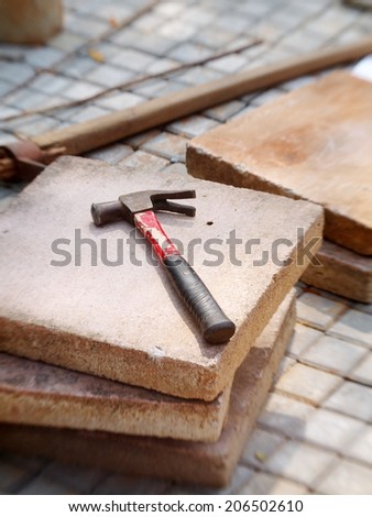 middle size steel hammer with rubber grip laying on a concrete floor path tile on a construction site outdoor