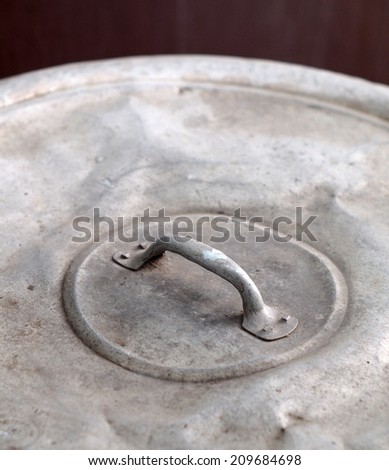 top view close up of hand grip of a large size old used aluminum round water jar pot cover for rainwater ceramic jar in country Thailand