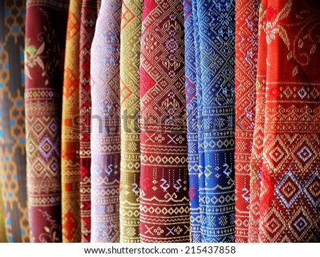 artistic variety shade tone colors ornaments patterns of thai silk textiles with traditional cultural decoration ornaments design by village people hanging in a street market in KHONKAEN, THAILAND