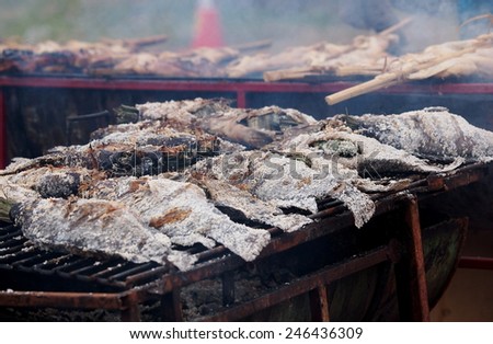 fresh delicious grilled fish, tilapia, nile fish with salt.  dark burn skin with charcoal outdoor for sale on street market in THAILAND