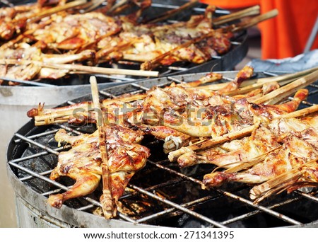 fresh delicious grilled chicken with salt and traditional source with yellow and dark burn skin with charcoal outdoor in the real environment for sale on street market in THAILAND