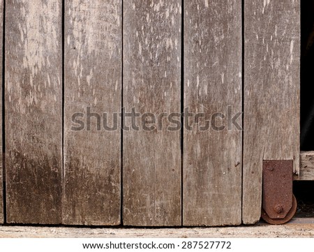 old aged abandoned weathered wood surface of a gray color old country house door with rusty metal door fittings installed