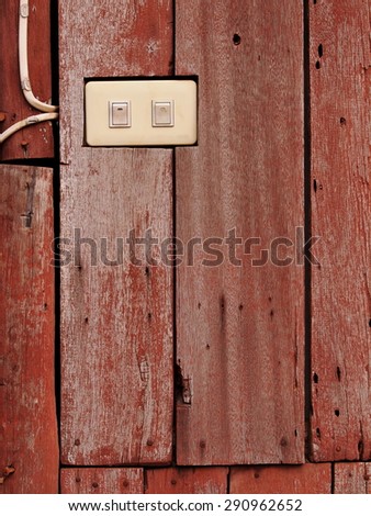 old aged abandoned weathered wood surface of a red brown color old country house external wall with white plastic electric switches installed