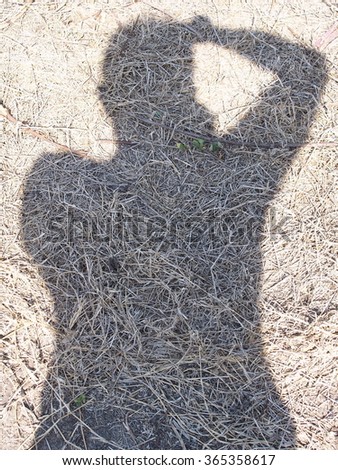 Photographer\'s shadow on the farm floor, self portrait silhouette outline on yellow brown dried grass hay straw under natural sunlight in an organic farm