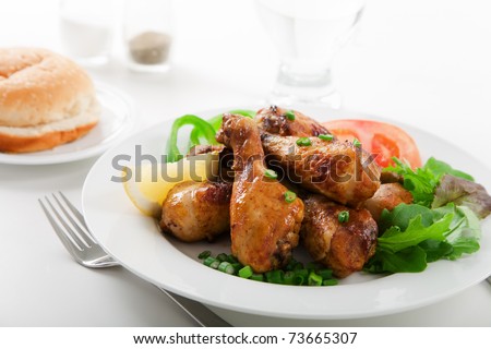 Roasted chicken drumsticks and salad on white plate