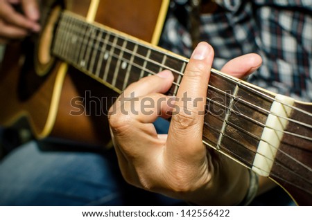 Acoustic guitar being played, Fingers holding a chord.