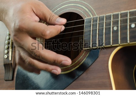 Acoustic guitar being played, Fingers holding a chord.