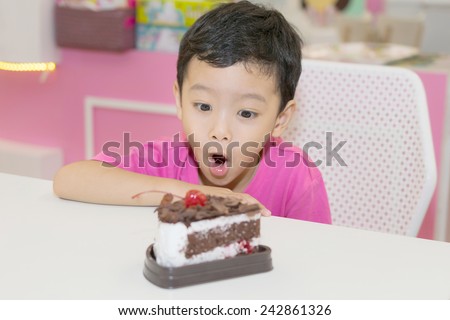 Little cute boy looking at a cake on the table.