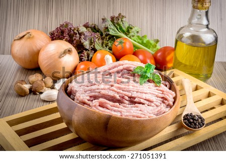 Raw ground meat in wood bowl. Minced pork on a background of fresh organic vegetables