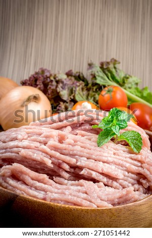 Raw ground meat in wood bowl. Minced pork on a background of fresh organic vegetables