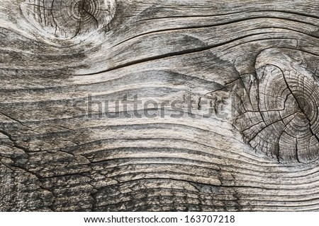 Old, weathered, rotten plank, with two large wood knots and rough textured, cracked, dilapidated surface.