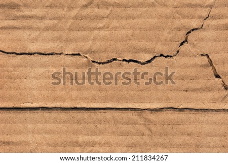 Photograph of recycle brown corrugated striped cardboard, coarse grain, obsolete, torn, grunge texture sample.