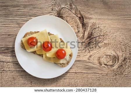 White Porcelain Plate, with Sandwich made of three fresh ripe juicy Tomatoes and Edam Cheese slices, placed on an old, wooden roughly treated, weathered, cracked Butcher Block surface.