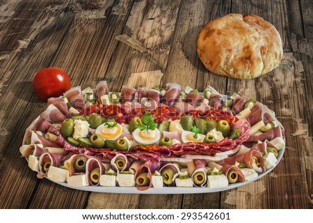 Plateful of Serbian Meze with domestic Pita Bread loaf and Tomato, placed on very old, weathered, cracked, scratched, peeled off, Wooden Table.