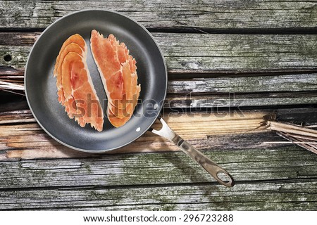 Cured Pork Ham Slices, in Teflon Frying Pan, on Old, Weathered, Cracked, Wooden Picnic Table covered with Moss Patches.