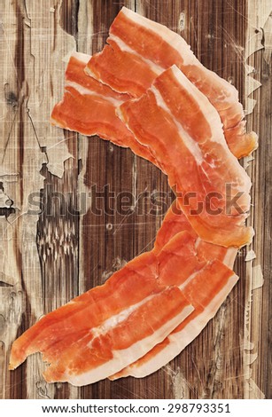 Dry Cured Smoked Pork Ham Prosciutto Slices Isolated on very Old Weathered Cracked Wooden Table Surface.