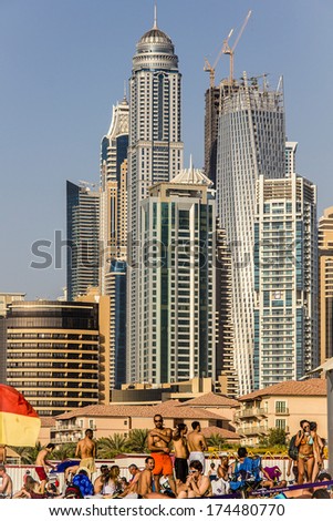 DUBAI - MARCH 21, 2013: People on beach in front of residential skyscrapers and hotels at Dubai Marina taken on March 21, 2013 in Dubai, United Arab Emirates.