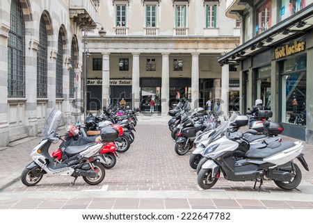 COMO MAY 15, 2014: Two lines of Italian scooters in front of an American store of the brand Foot Locker in an ancient European city taken on May 15, 2014 in Como, Italy