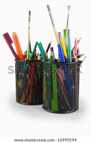 various old writing utensils in basket on white background