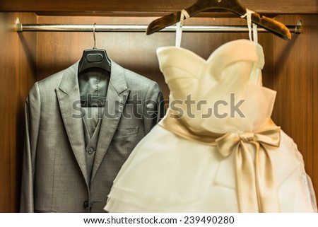 Bridegroom dress and bridal gown hanging in wardrobe