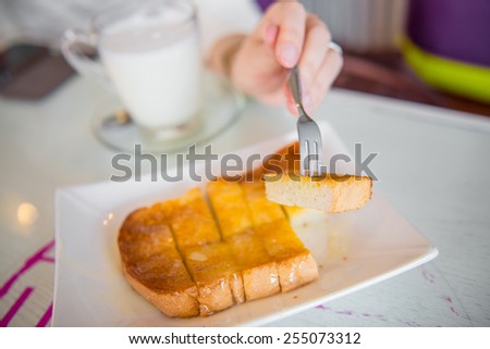 Fork in hand stab the butter bread toast and condensed milk