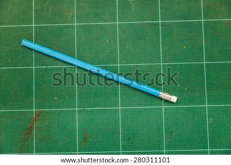 A pencil on a green cutting mat