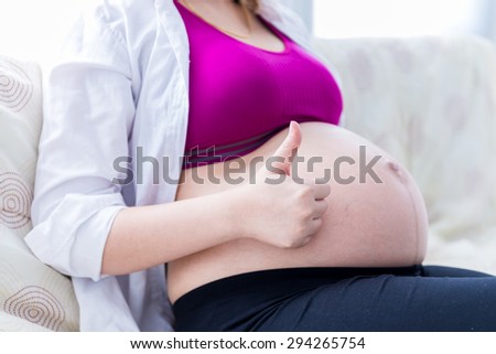 Pregnant woman show LIKE signal. Thumbs up. Good job.