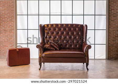 The red leather sofa with a big luggage in vintage room