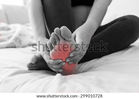 Pregnant woman massaging her painful foot, red hi-lighted on pain area