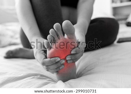 Pregnant woman massaging her painful foot, red hi-lighted on pain area
