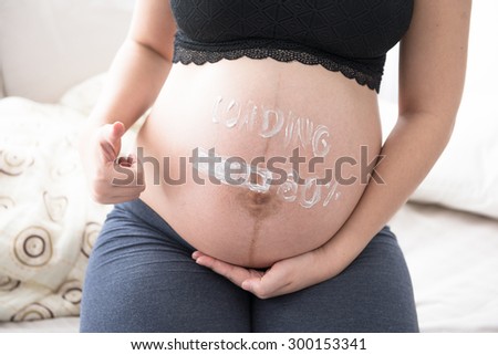 pregnant woman with painted on white paints cream - loading 80%, looking forward to long awaited child