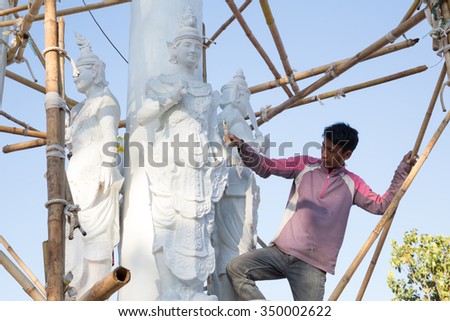 MAE SOT, TAK, THAILAND - DECEMBER11 : Unidentified Myanmar man is painting white stucco gods at Wat Tha Add, Mae Sot, Tak, Thailand  on December11, 2015.