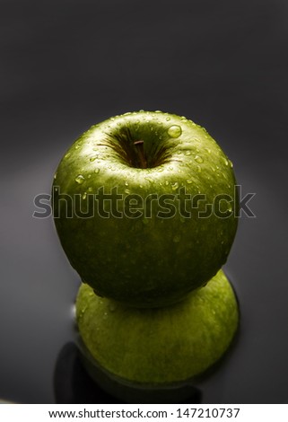 Two apples one over another inside water with drops