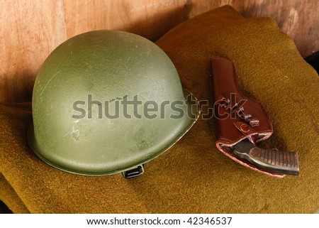 Military helmet and revolver on brown blanket