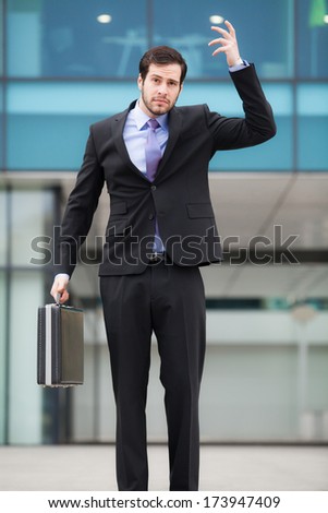 confused businessman in front of an office building with a briefcase