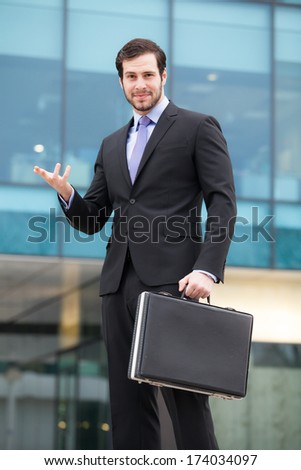 handsome and successful businessman in front of an office building with a briefcase