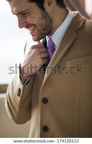 Profile of a businessman smiling in a coat with tie and blue shirt