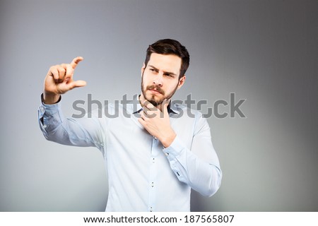 serious man in blue shirt holding something imaginary between fingers