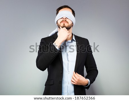 elegant thinking blindfolded man on grey background