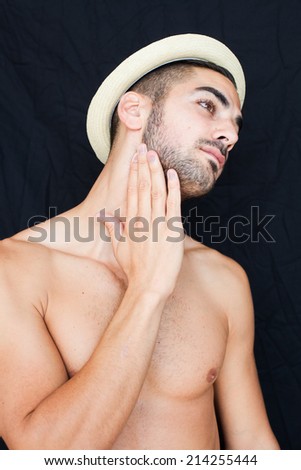 Handsome man half naked with hat smiling on black backgound