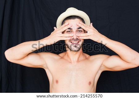 Handsome man half naked with hat smiling on black backgound