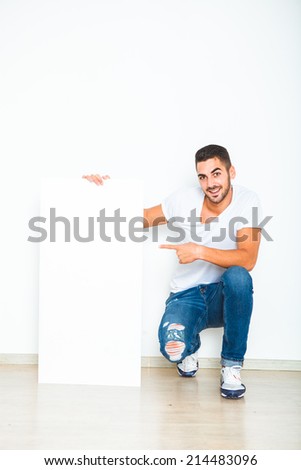 Young handsome man casual dressed smiling and showing a blank panel on white background