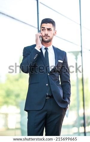 elegant business handsome man talking at cellphone outside on the street