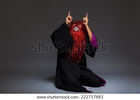 halloween monster with red face on dark background, pointing directions