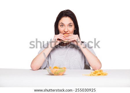 healthy versus junk food concept with a natural woman heaving in front fruits meal and choosing fries with hamburger, isolated on white