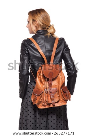 back of a young girl dressed in leather jacket with brown leather backpack on white
