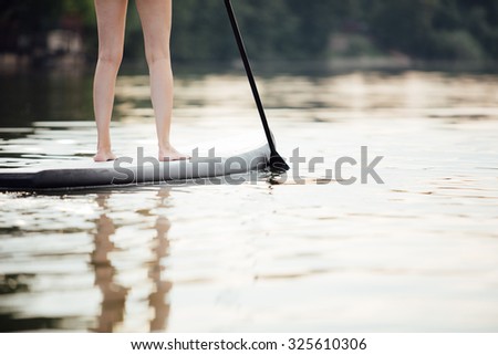 close-up of a woman legs on paddle board in water